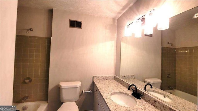 full bathroom featuring tiled shower / bath combo, toilet, a textured ceiling, and vanity