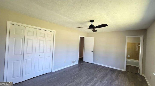 unfurnished bedroom with ceiling fan, dark wood-type flooring, a textured ceiling, and a closet