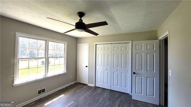 unfurnished bedroom featuring ceiling fan, dark hardwood / wood-style floors, and a textured ceiling