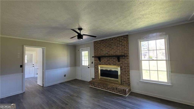 unfurnished living room with a brick fireplace, a textured ceiling, dark hardwood / wood-style floors, and crown molding