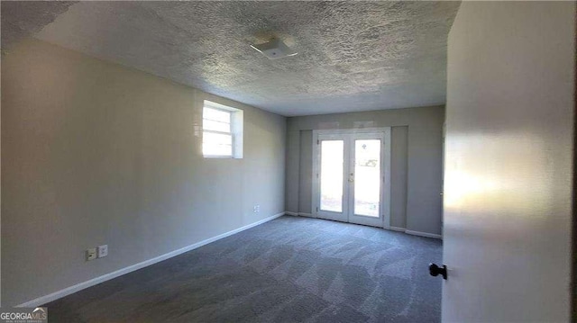 unfurnished room featuring dark colored carpet, a textured ceiling, and french doors