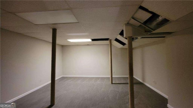 basement with a drop ceiling and dark carpet