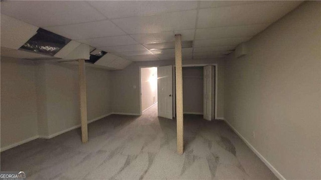 basement featuring a paneled ceiling and light carpet