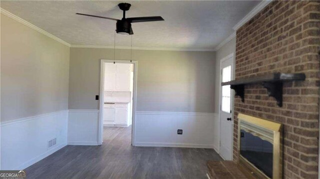 unfurnished living room with ceiling fan, dark hardwood / wood-style flooring, ornamental molding, and a fireplace