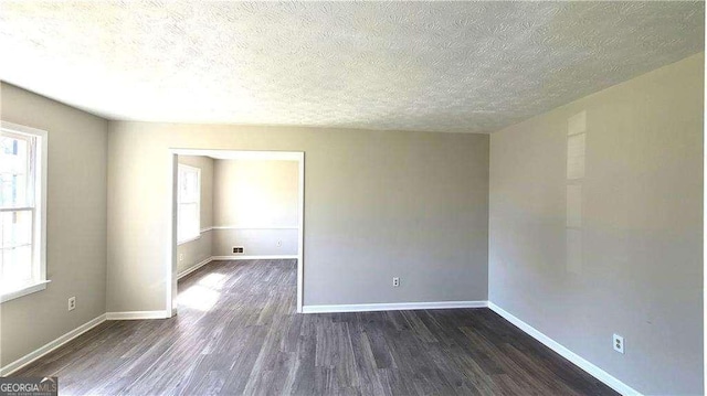 unfurnished room with a textured ceiling and dark hardwood / wood-style flooring