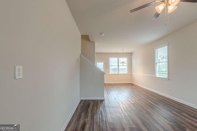 unfurnished living room featuring dark wood-type flooring and ceiling fan