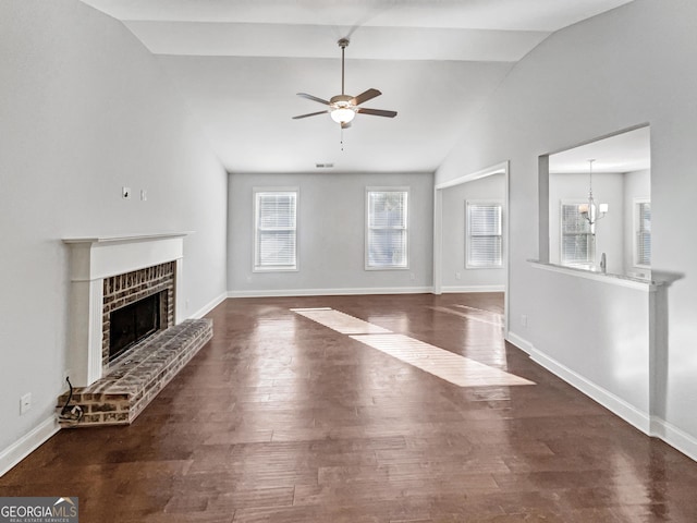 unfurnished living room featuring a fireplace, a healthy amount of sunlight, vaulted ceiling, and dark hardwood / wood-style flooring