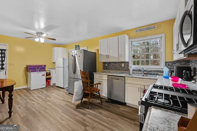 kitchen with sink, backsplash, white cabinetry, and appliances with stainless steel finishes