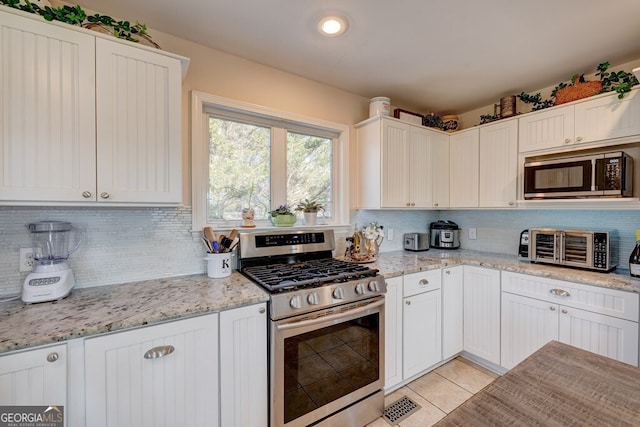 kitchen featuring light stone counters, white cabinetry, appliances with stainless steel finishes, and light tile patterned flooring