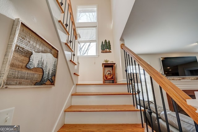 stairway with wood-type flooring and a towering ceiling