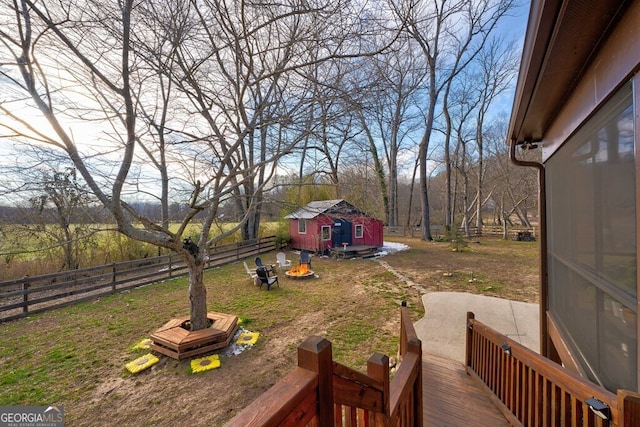 view of yard featuring a deck, an outdoor structure, and a fire pit