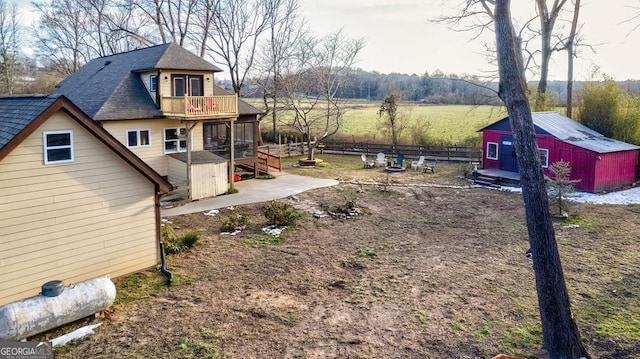 view of yard featuring a balcony, a storage shed, and a rural view