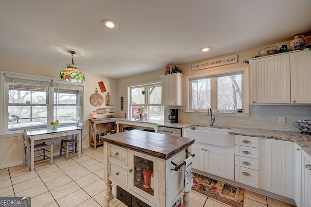 kitchen featuring sink, hanging light fixtures, white cabinets, and butcher block countertops