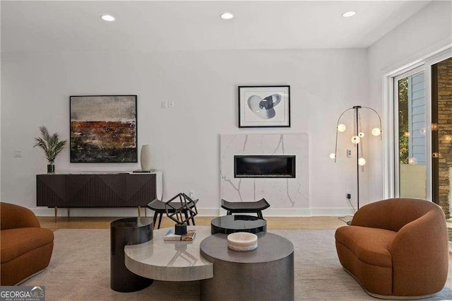 living room with a high end fireplace and light hardwood / wood-style flooring