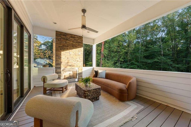 sunroom / solarium featuring an outdoor stone fireplace and ceiling fan