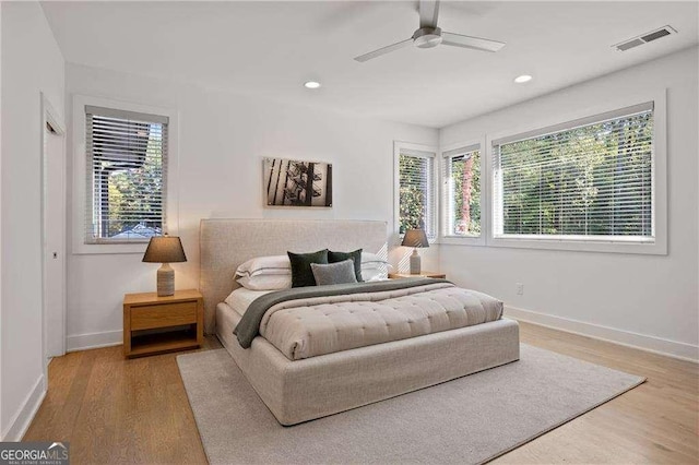 bedroom featuring ceiling fan, multiple windows, and wood-type flooring