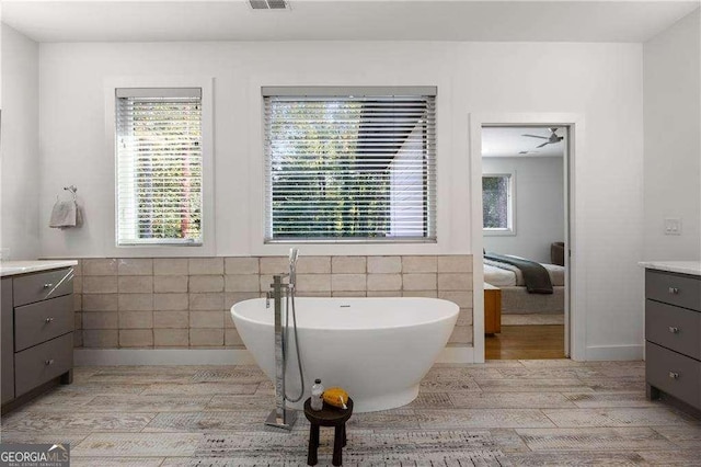 bathroom featuring a tub, hardwood / wood-style flooring, vanity, and tile walls