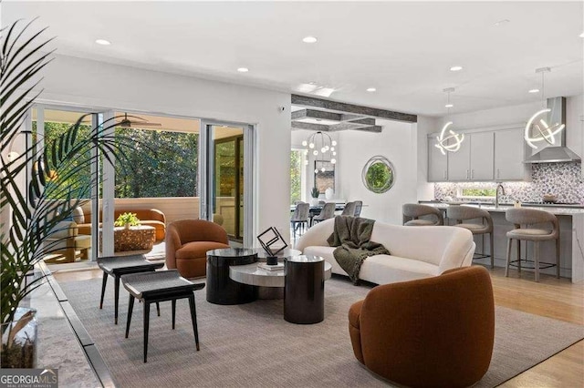 living room with sink, beam ceiling, and light hardwood / wood-style floors