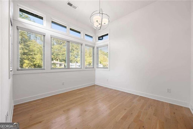 spare room with a chandelier and light hardwood / wood-style flooring