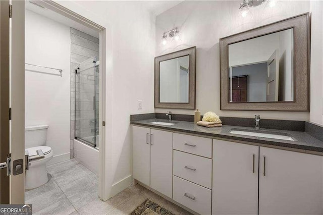 full bathroom with combined bath / shower with glass door, vanity, toilet, and tile patterned flooring