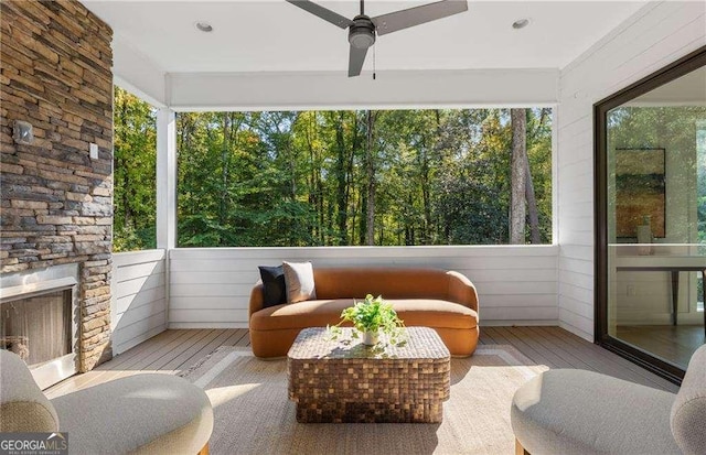 sunroom featuring ceiling fan, a wealth of natural light, and an outdoor stone fireplace