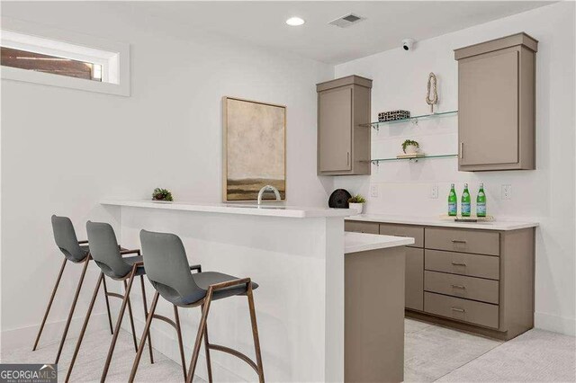 bar with sink, light colored carpet, and gray cabinets