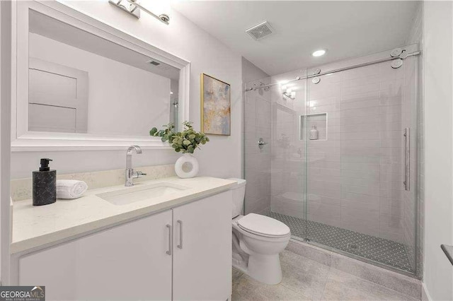 bathroom featuring vanity, toilet, and a shower with shower door