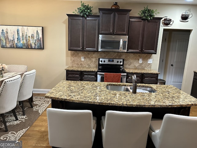 kitchen with tasteful backsplash, an island with sink, appliances with stainless steel finishes, and sink