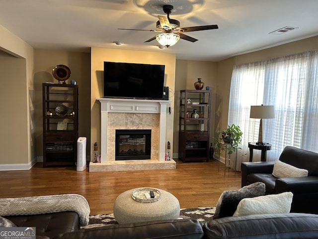 living room featuring ceiling fan, wood-type flooring, and a tile fireplace