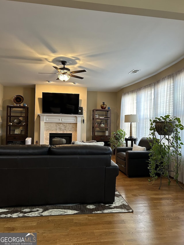 living room with a tile fireplace, hardwood / wood-style floors, and ceiling fan