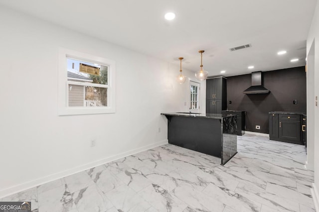 kitchen with kitchen peninsula, hanging light fixtures, a breakfast bar area, and wall chimney range hood