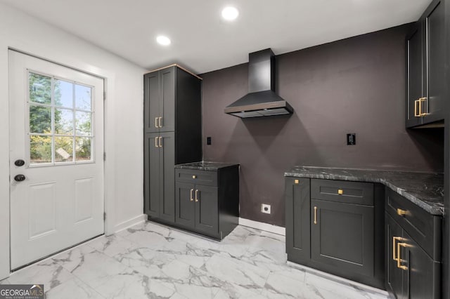 kitchen with wall chimney range hood and dark stone countertops