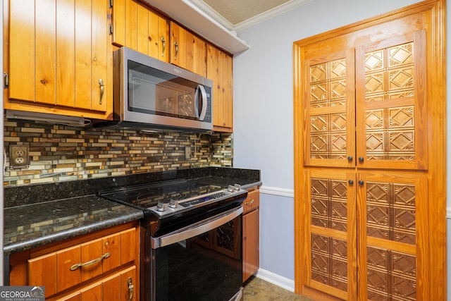 kitchen with dark stone counters, ornamental molding, appliances with stainless steel finishes, and tasteful backsplash