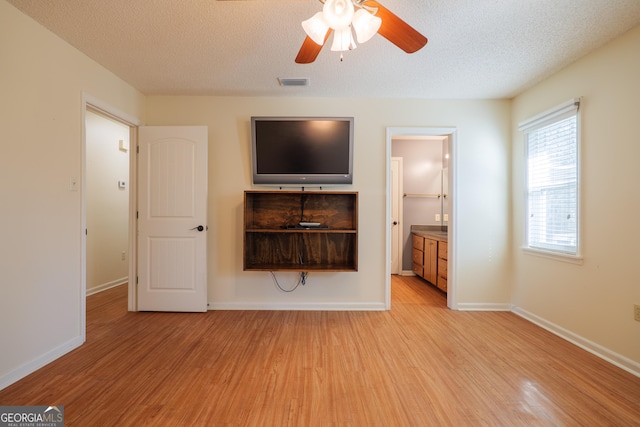 unfurnished living room with a textured ceiling, light hardwood / wood-style flooring, and ceiling fan