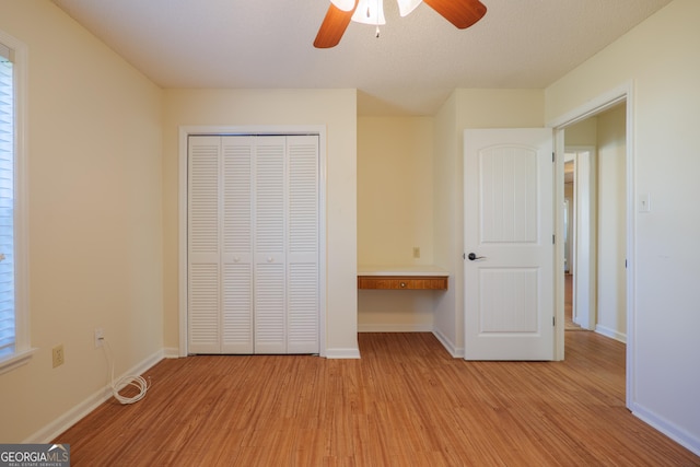 unfurnished bedroom with light hardwood / wood-style flooring, a closet, and ceiling fan