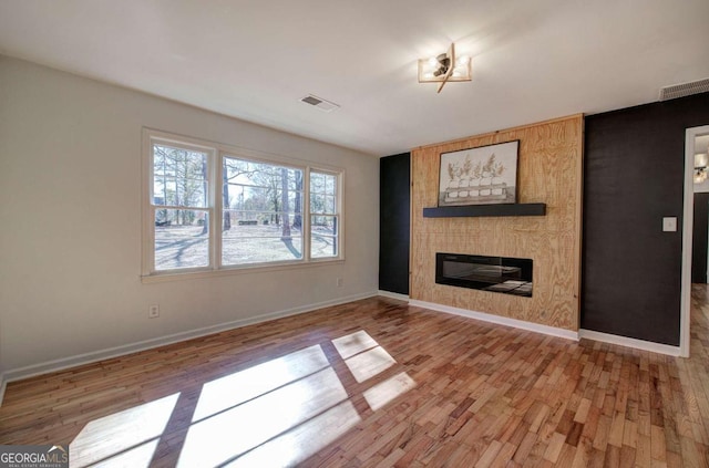 unfurnished living room featuring wood-type flooring and a large fireplace