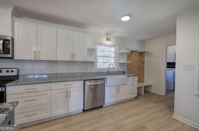 kitchen with backsplash, appliances with stainless steel finishes, washer / dryer, and white cabinets