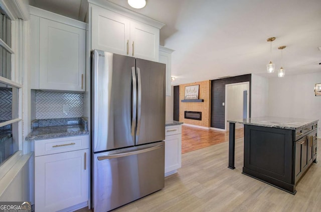 kitchen with stainless steel refrigerator, white cabinetry, and light hardwood / wood-style flooring