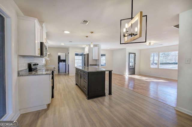 kitchen with pendant lighting, light hardwood / wood-style flooring, white cabinets, and a kitchen island