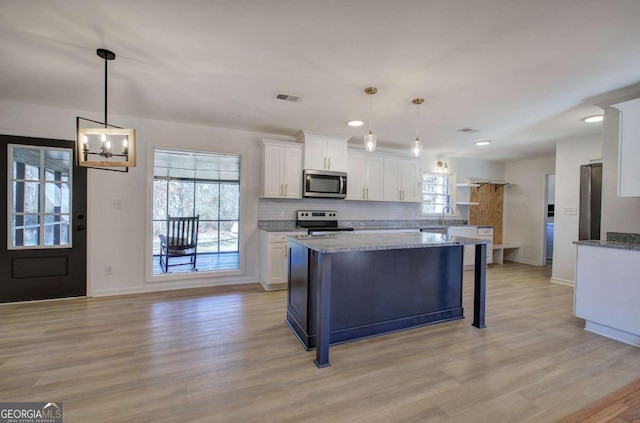 kitchen with white cabinetry, appliances with stainless steel finishes, light stone counters, and hanging light fixtures