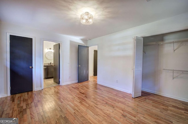 unfurnished bedroom featuring a closet, connected bathroom, and light hardwood / wood-style flooring