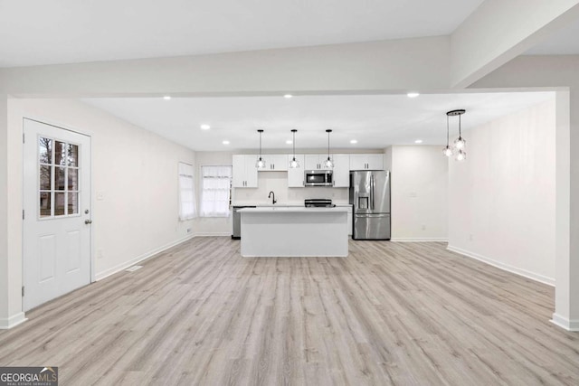 kitchen featuring pendant lighting, white cabinets, a center island, stainless steel appliances, and light wood-type flooring