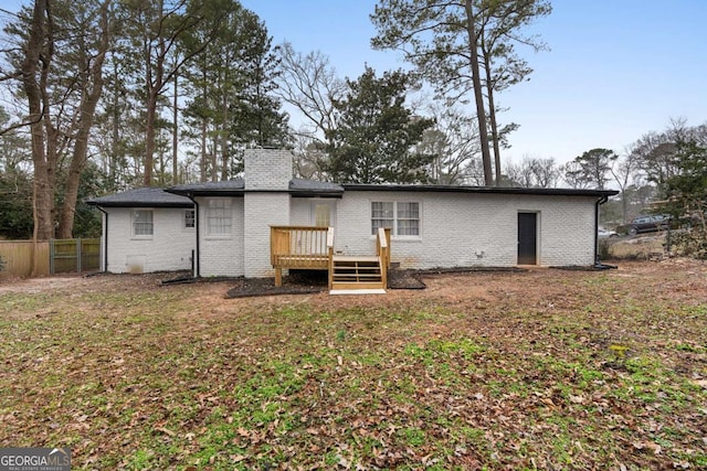 rear view of house featuring a deck and a lawn