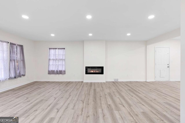 unfurnished living room with light wood-type flooring and heating unit