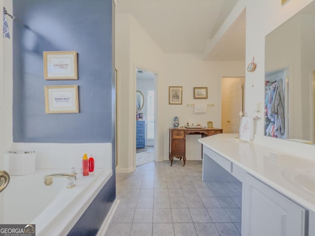 bathroom featuring tiled tub, tile patterned floors, and vanity