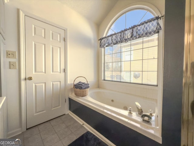 bathroom with vaulted ceiling, a wealth of natural light, tile patterned floors, and a washtub