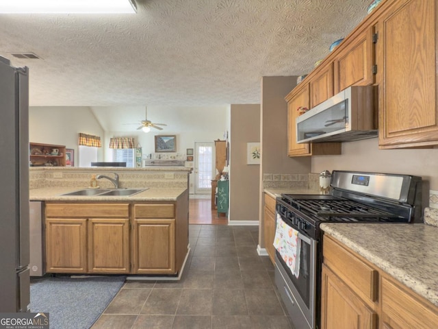 kitchen featuring kitchen peninsula, ceiling fan, appliances with stainless steel finishes, sink, and a textured ceiling