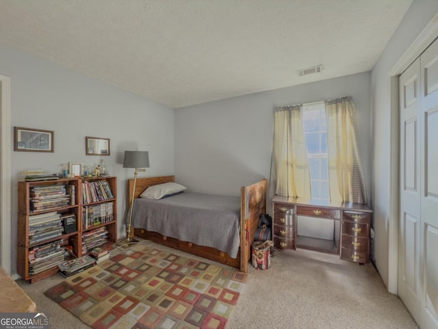 bedroom featuring a closet, a textured ceiling, and light carpet