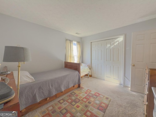 carpeted bedroom with a textured ceiling and a closet