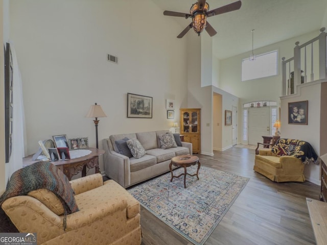 living room featuring wood-type flooring, a towering ceiling, and ceiling fan